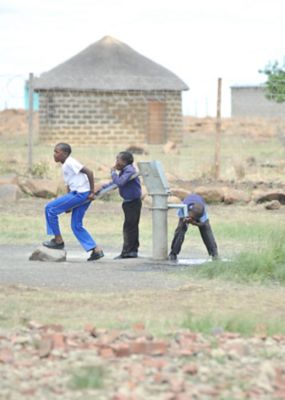 Boys drinking from water well