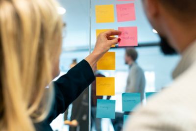Employees looking at sticky notes on a board.