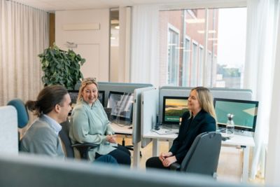 Employees having a conversation in front of an office window.  