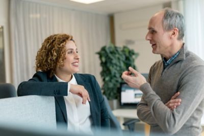 Employees conversing while leaning on a desk barrier. 