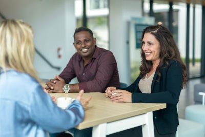 A diverse group of colleagues in a discussion around a table in the office.