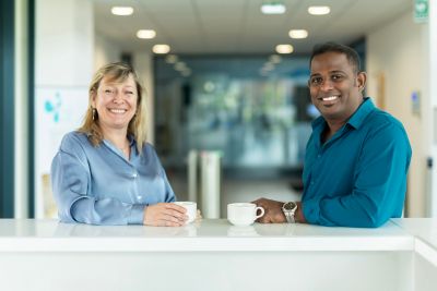 En man och en kvinna tar en kaffe ihop ståendes i ett kontorslandskap 