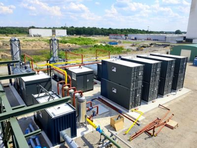 A large industrial facility with several large industrial boilers and superheaters delivering 60.000 kg of steam. The machines are connected to each other with pipes. 