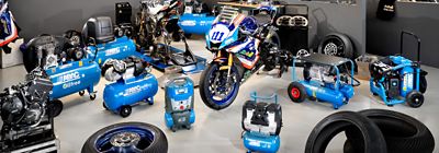 ABAC piston compressors displayed in garage with motorbikes