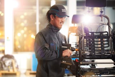 Atlas Copco employee using hand-held tool in car seat manufacturing. 