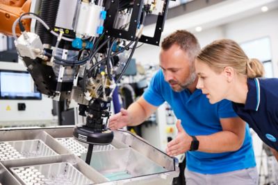 Customer and Atlas Copco technician with adhesive dispensing system in production