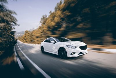 White car speed driving on asphalt road at daytime