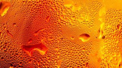 Macro image showing condensation on a cold glass surface, the surface of a drop of cola drink,showcases the intricate texture of water droplets forming condensation on a chilled glass surface