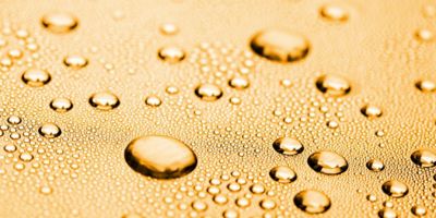 Close-up of water droplets spread across a textured surface, with varying droplet sizes creating a pattern that suggests condensation and moisture control.