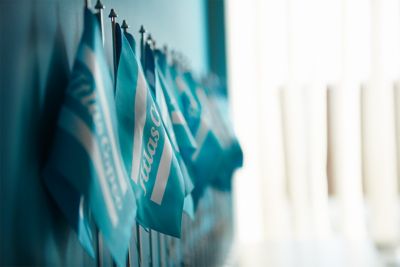 A photo of Atlas Copco flags with white logotype on blue background standing in a row in the office environment
