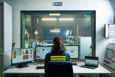 Back view of employee seated at workstation with desktop and laptop