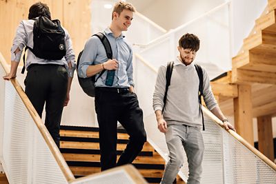 Image of graduates walking down the stairs together with backpacks on