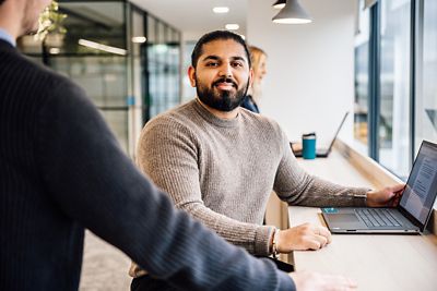 Male employee smiling at camera whilst in a work environment