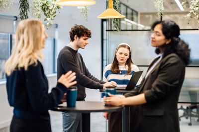 Colleagues engage in an informal discussion in office cafeteria. This image captures teamwork, communication, and business synergy in action, highlighting the professional and cooperative atmosphere.