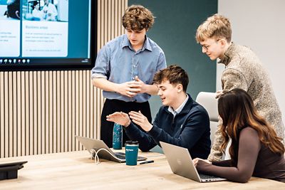 A group of students working on laptops in a meeting 