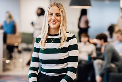 A female employees smiling at the camera with lots of other employees blurred out in the background