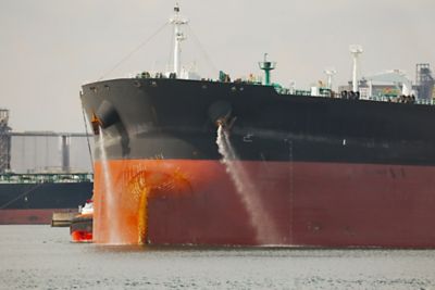 Large crude oil tanker ship pumping out ballast water when coming into port
