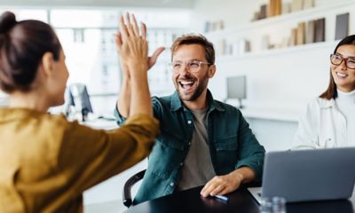 Two young business professionals celebrating teamwork in an office.