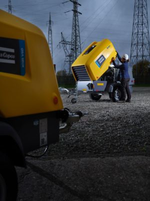 Atlas Copco employee working with a mobile air compressor