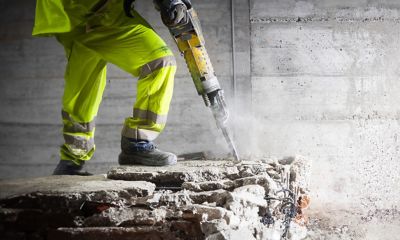 Construction worker using heavy-duty jackhammer tool and breaking reinforced concrete for references