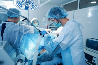 Side view of man doctor in surgery room providing narcosis during operation with anesthesia machine