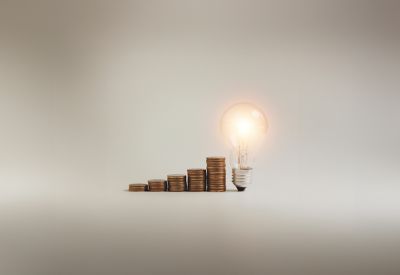 Efficiency concept - Bulb with coins in grey background