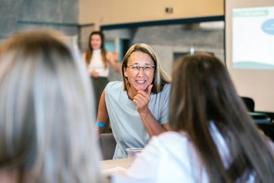 A woman is about to start laughing in a conversation with two colleagues. ​