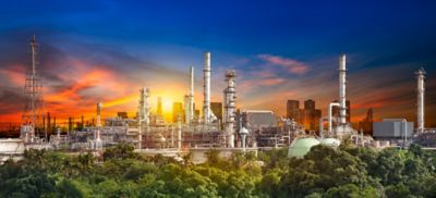 Oil refiner industry in rural scene on sunset background