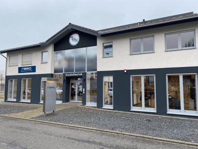 A two-story white and blue building with the nano-purification solutions sign on the front, to convey our Germany location