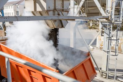 Cropped of heavy industrial dump truck unloading hot asphalt at plant for construction industry production