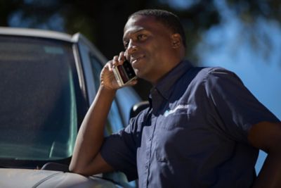 Close up of male service tech leaning on van hood while taking a call