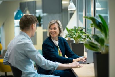 Two colleagues smiling at each other in front of a laptop