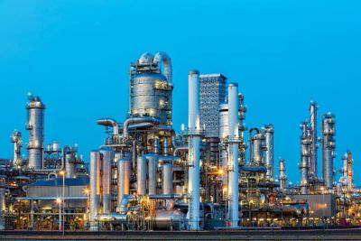 A large, modern petrochemical plant at dusk in industrial district near Rotterdam, Netherlands, Benelux, Europe. Distillation towers and other installations are visible against blue sky