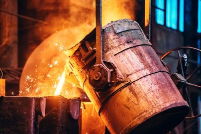 Molten metal pour from ladle Into sand mold. Iron casting process in metallurgy foundry plant, heavy industry.