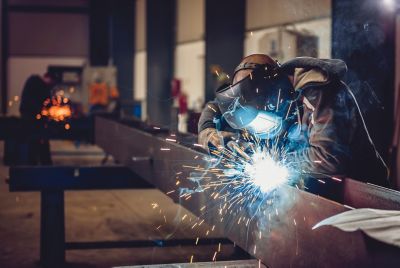 Industrial Welder With Torch and Protective Helmet in big hall welding metal profiles