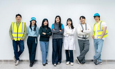 Group of colleagues posing in front of wall.