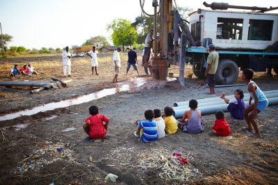 Drilling for water with children watching