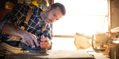 Man working in a wood workshop with orbital air sander