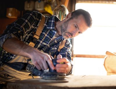 Man working in a wood workshop with orbital air sander-squared