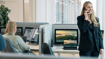 An employee having a conversation on her cell phone while a colleague works at a desk. 