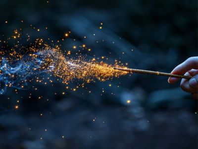 Optimising air compressor - A hand holding a magic wand casting sparkling golden particles against a dark wooded background