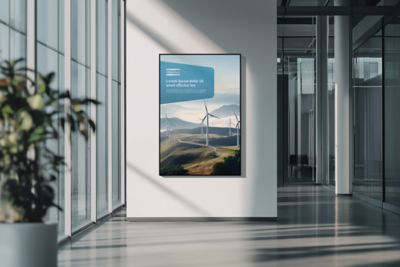 A hallway with the sun shining through glass windows on a Atlas Copco poster on the wall.