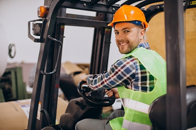 Employee working at warehouse and driving forklift.