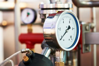 정밀 압력 게이지를 사용하는 산업 설비 클로즈업 – 검교정 및 유지관리 장비