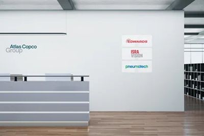 Reception area branding with the Atlas Copco Group logotype to the left and other brands to the right.