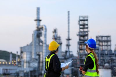 Two female engineer discussion together at refinery industry plant at industry factory center area.