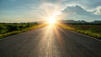 Road towards the horizon, sun on its way up in the background.