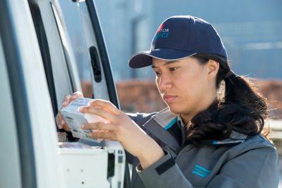 Female service technician taking a part out of a service van