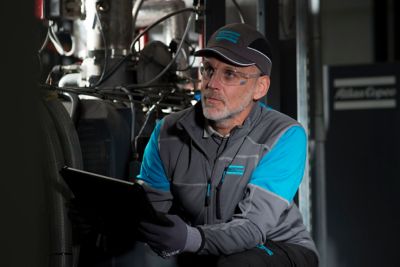 Male service technician in a working environment holding a tablet or pc