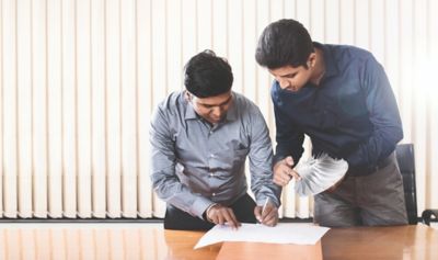 Zwei Männer im Hemd stehen an einem Tisch und betrachten gemeinsam ein Impeller.